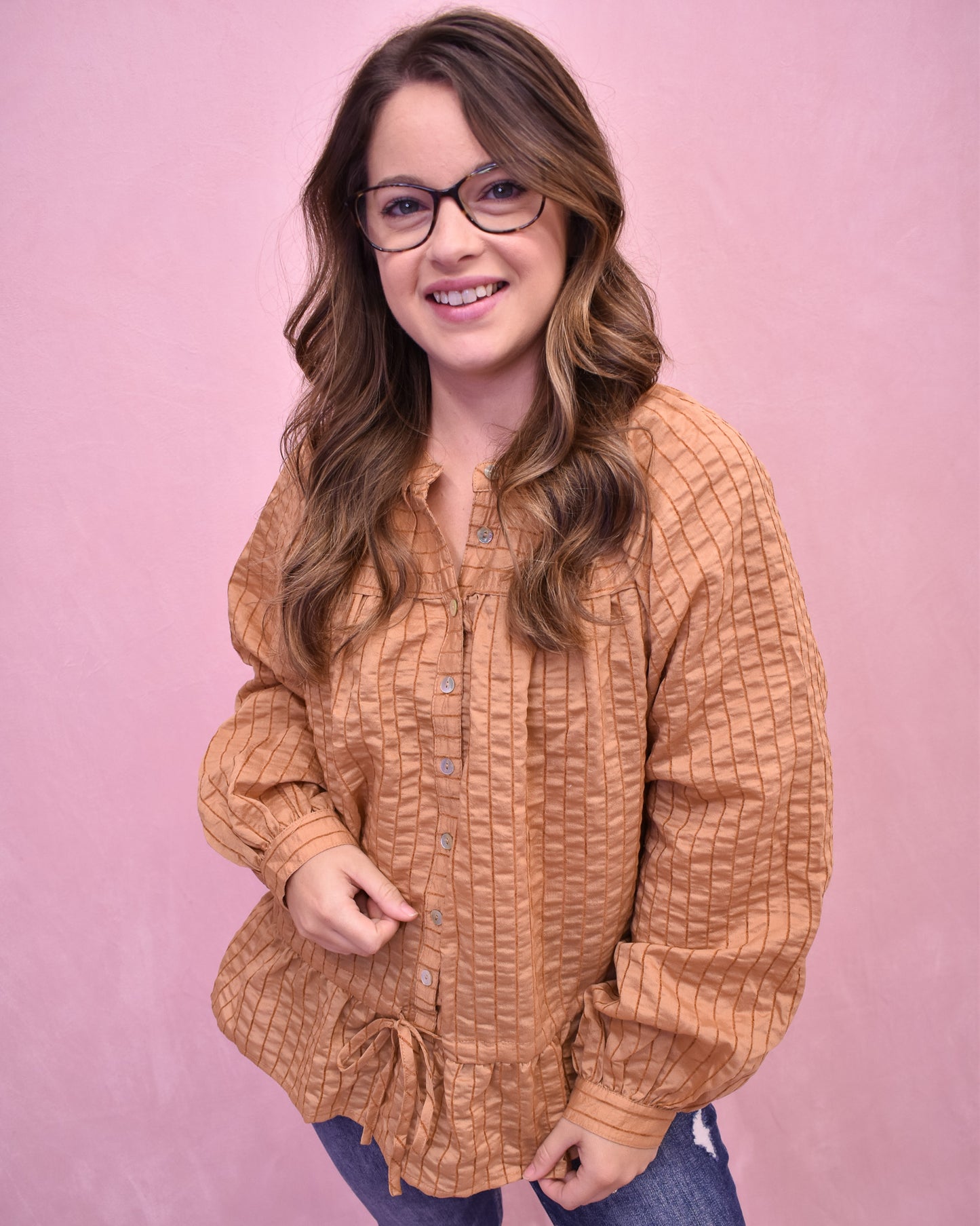 Woman wearing a brown textured shirt against a pink background