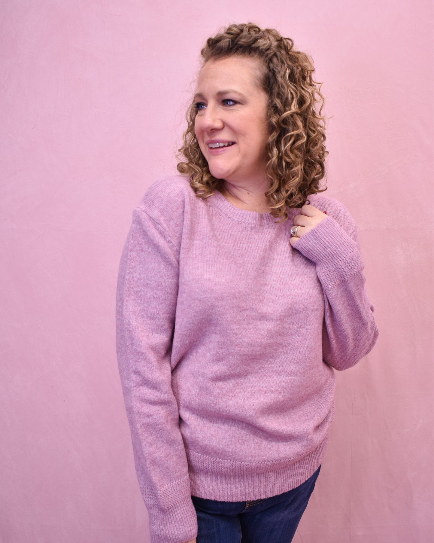 Woman wearing a pink sweater against a pink background
