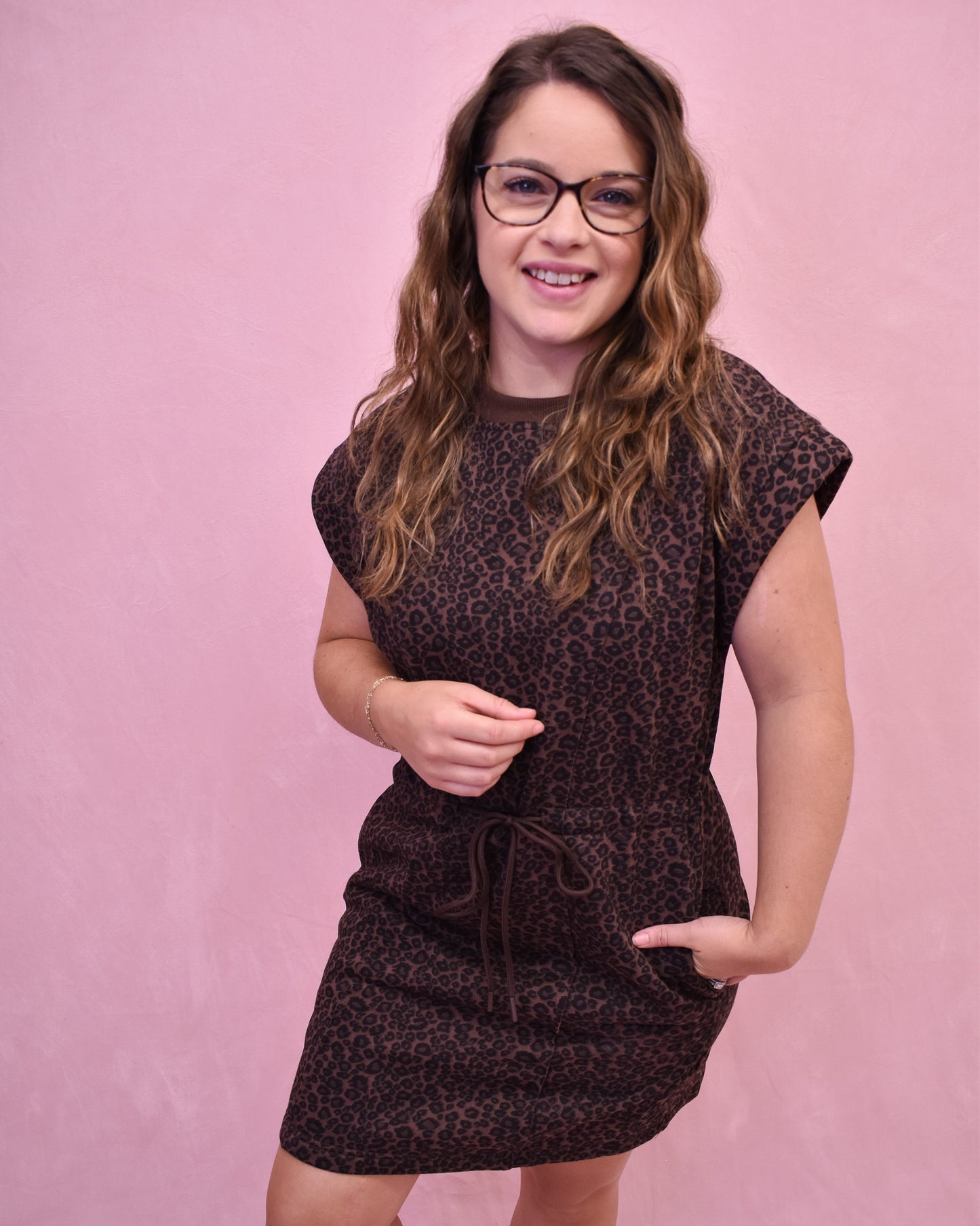 Woman wearing a patterned dress against a pink background