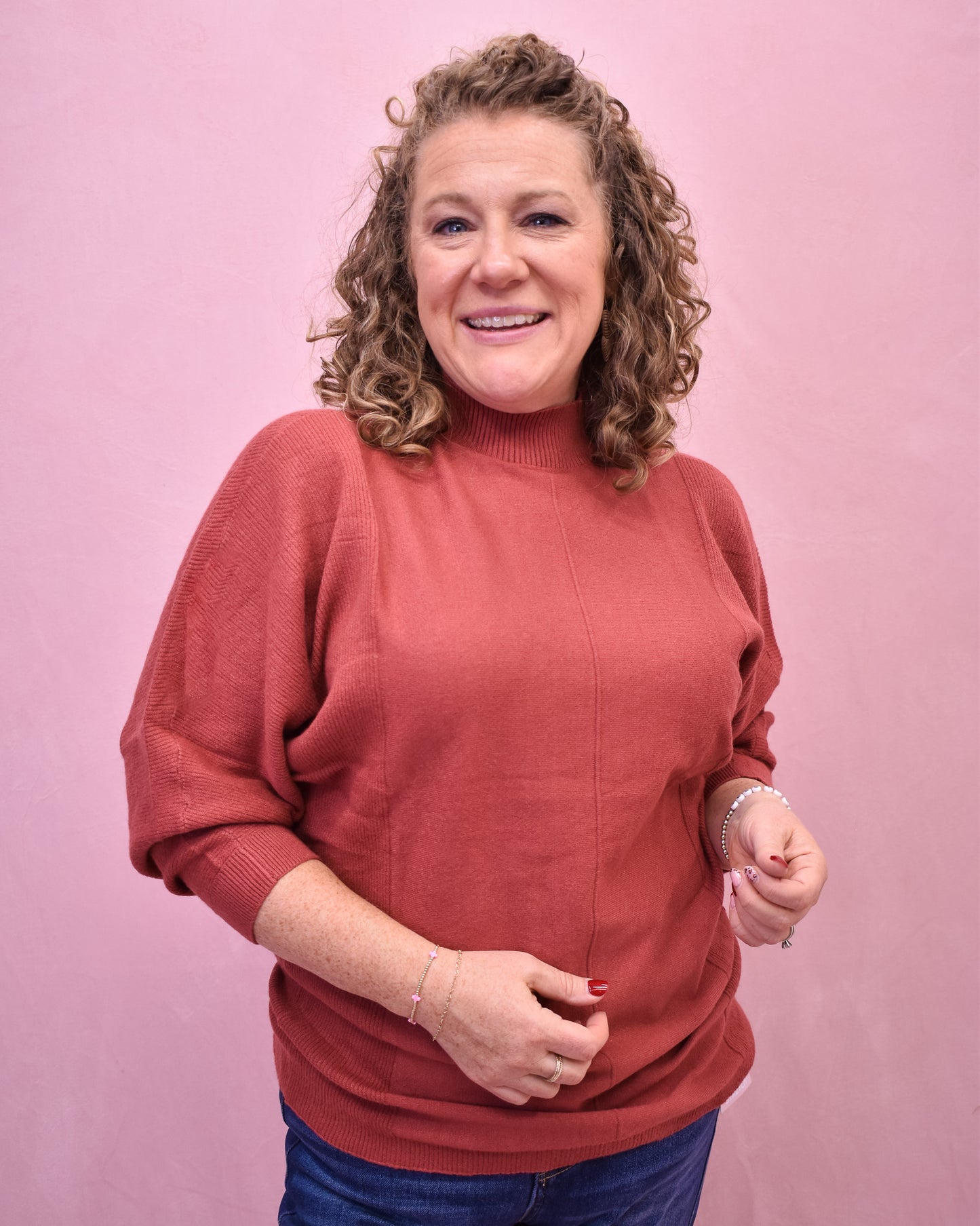 Woman wearing a red sweater against a pink background