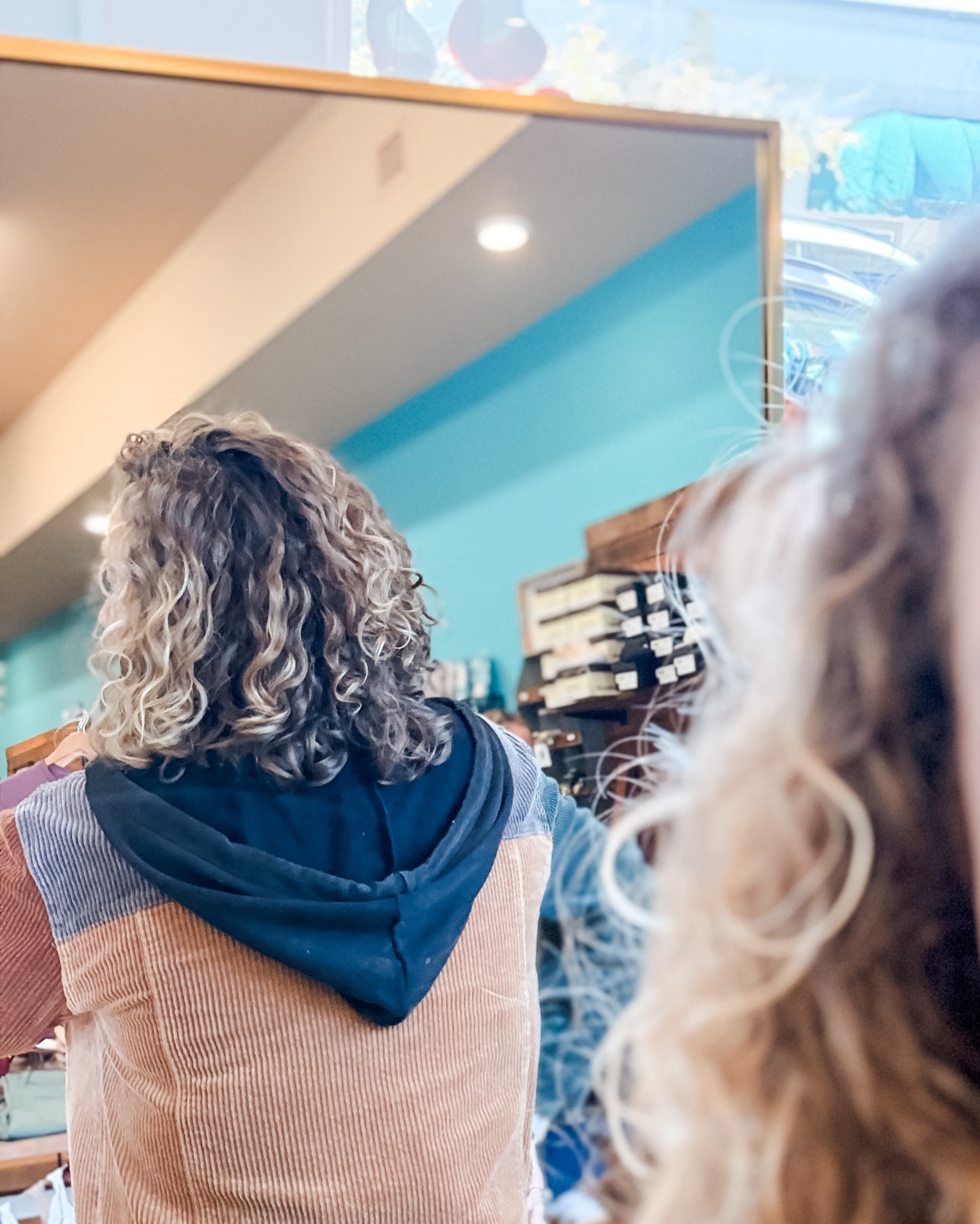 Person with curly hair looking at themselves in a mirror.
