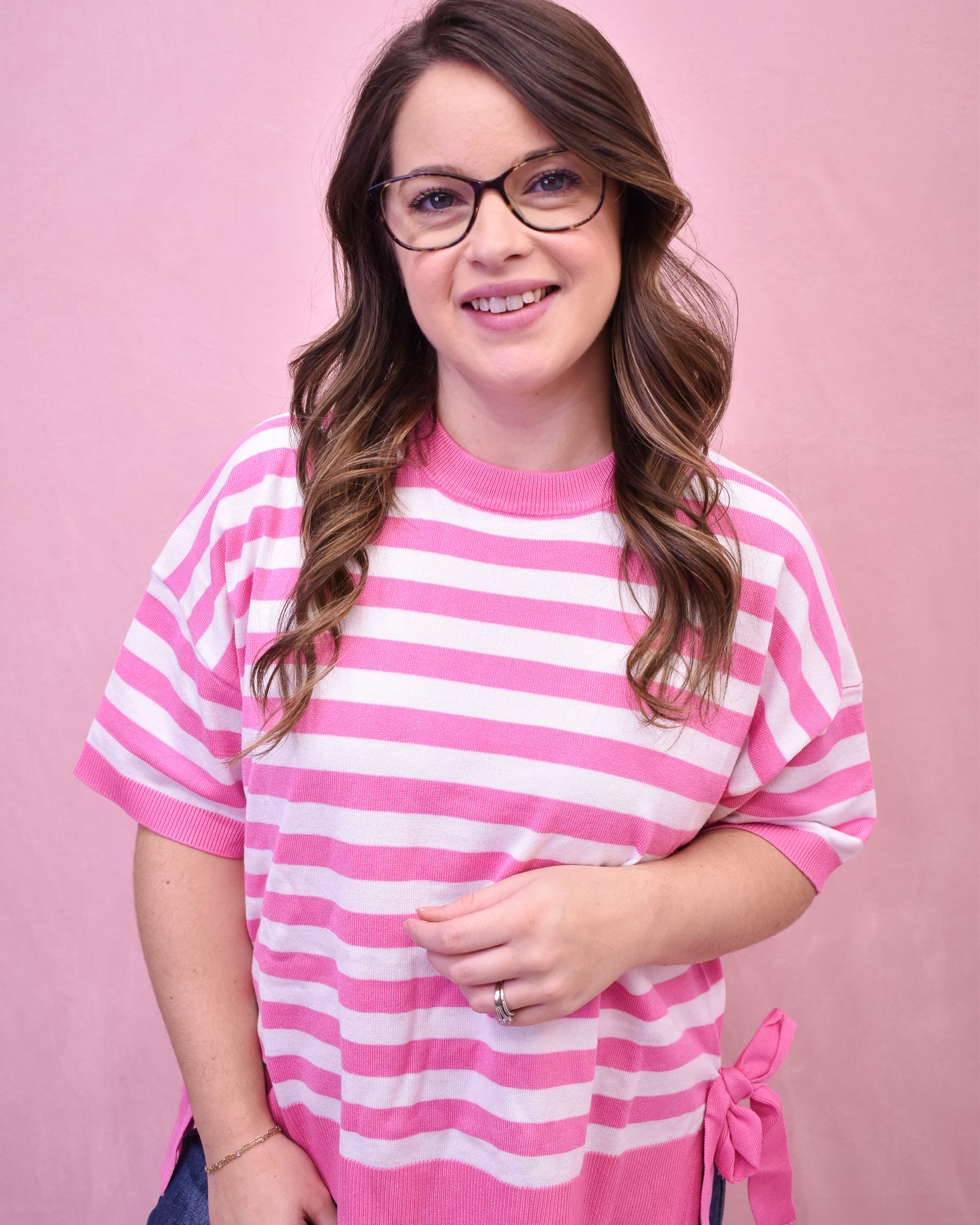 Woman wearing a pink and white striped shirt against a pink background