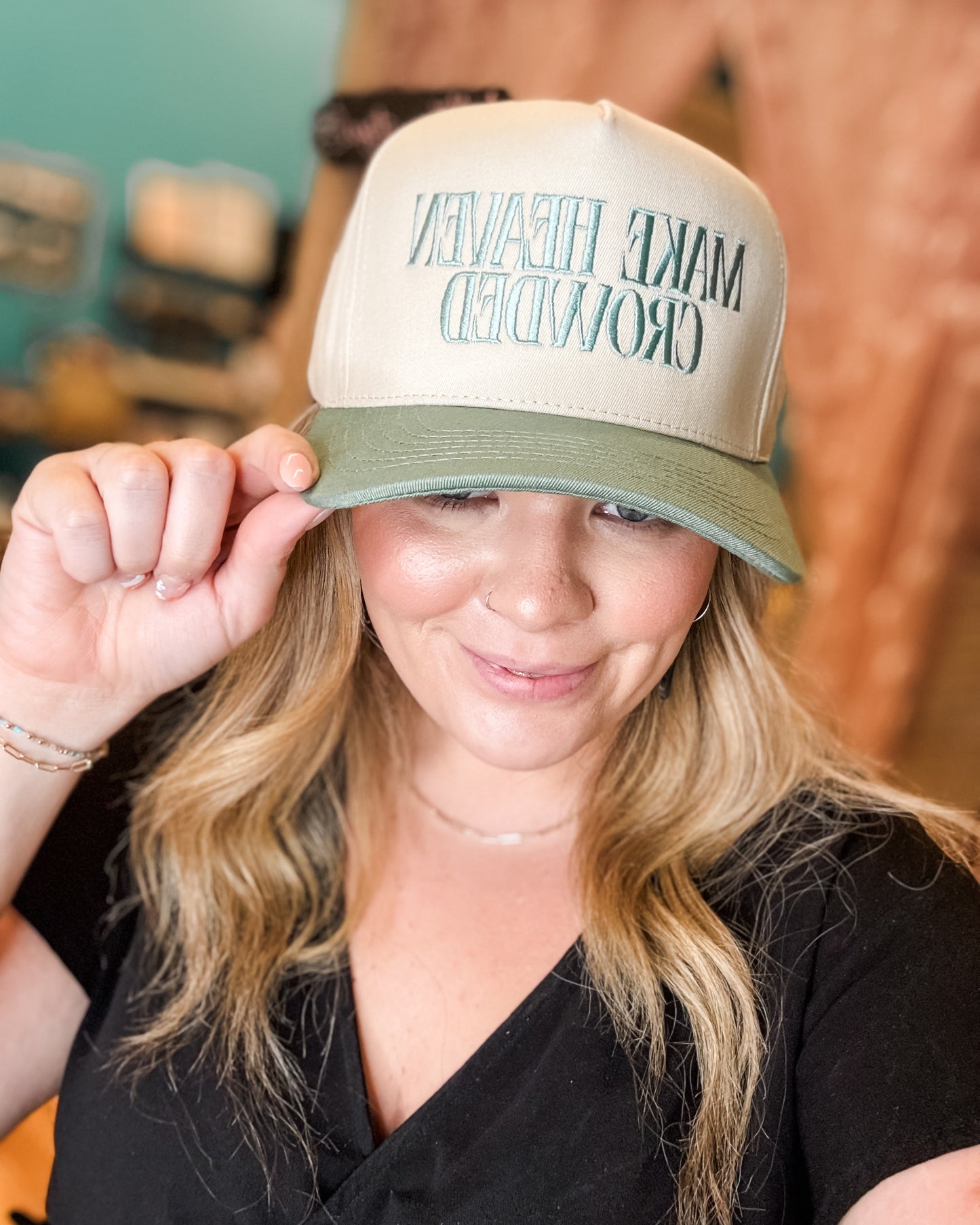 Person wearing a beige and green cap with text, indoors.