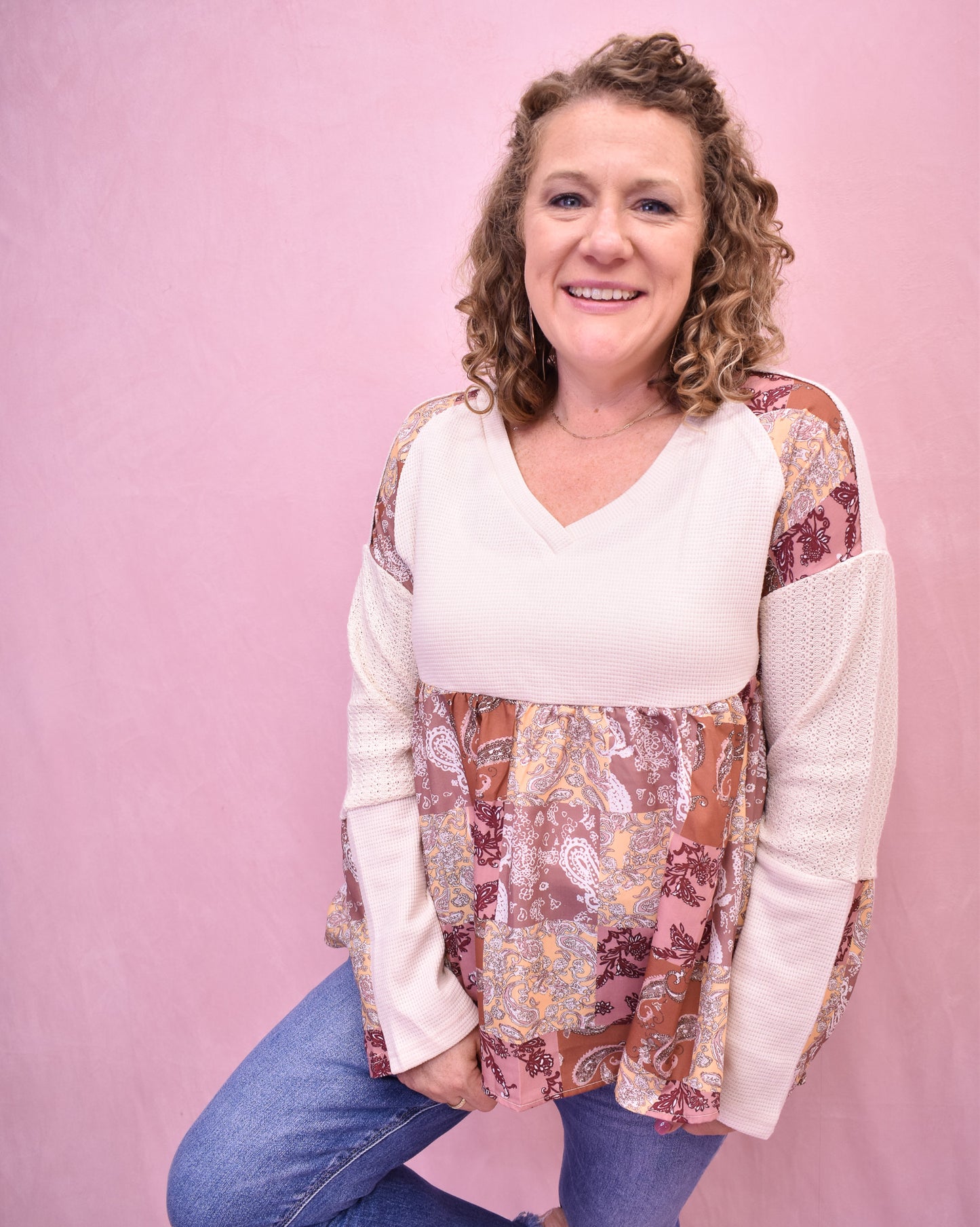 Woman wearing a patterned top with a pink background