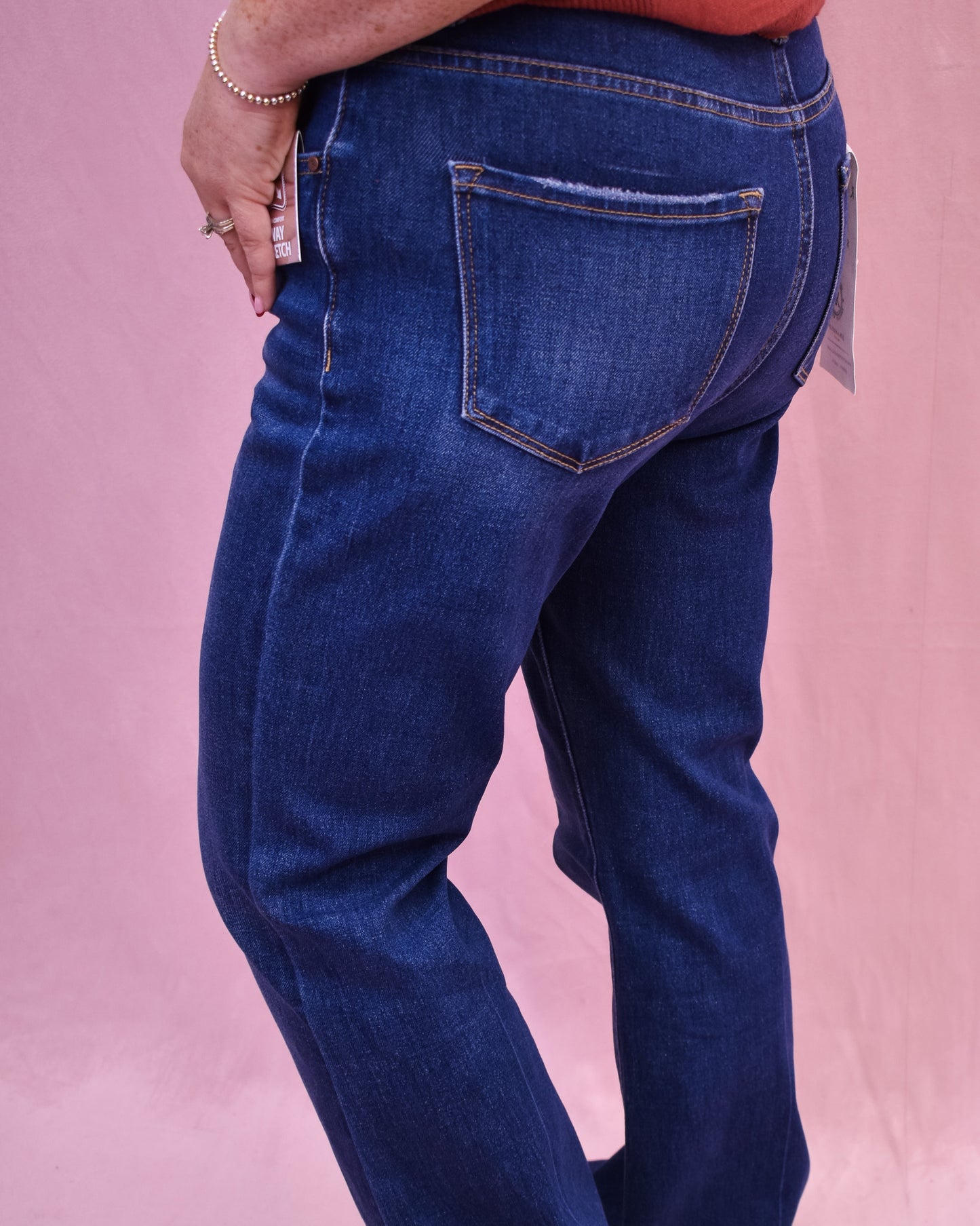 Blue jeans worn by a person on a pink background