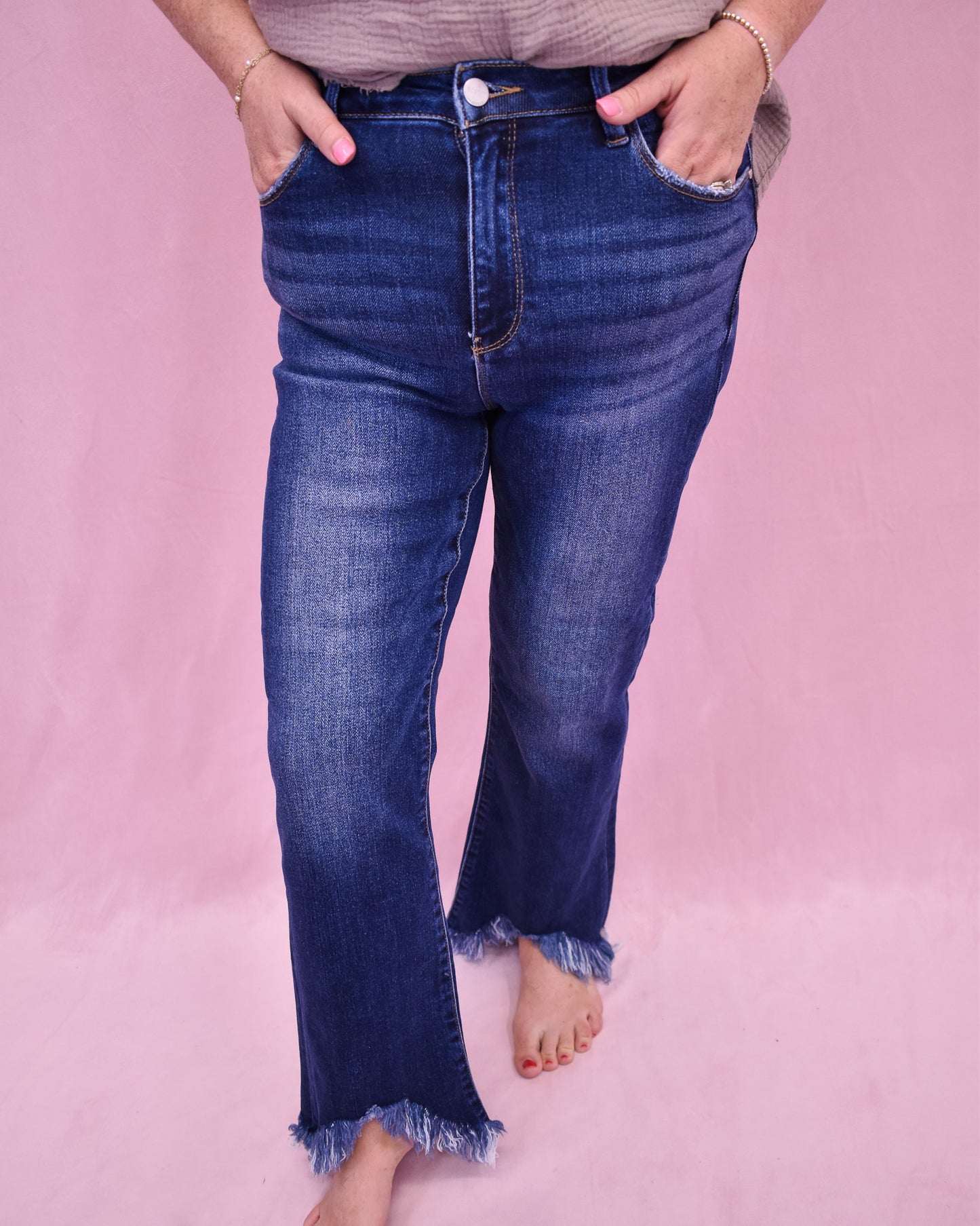 Person wearing blue jeans on a pink background