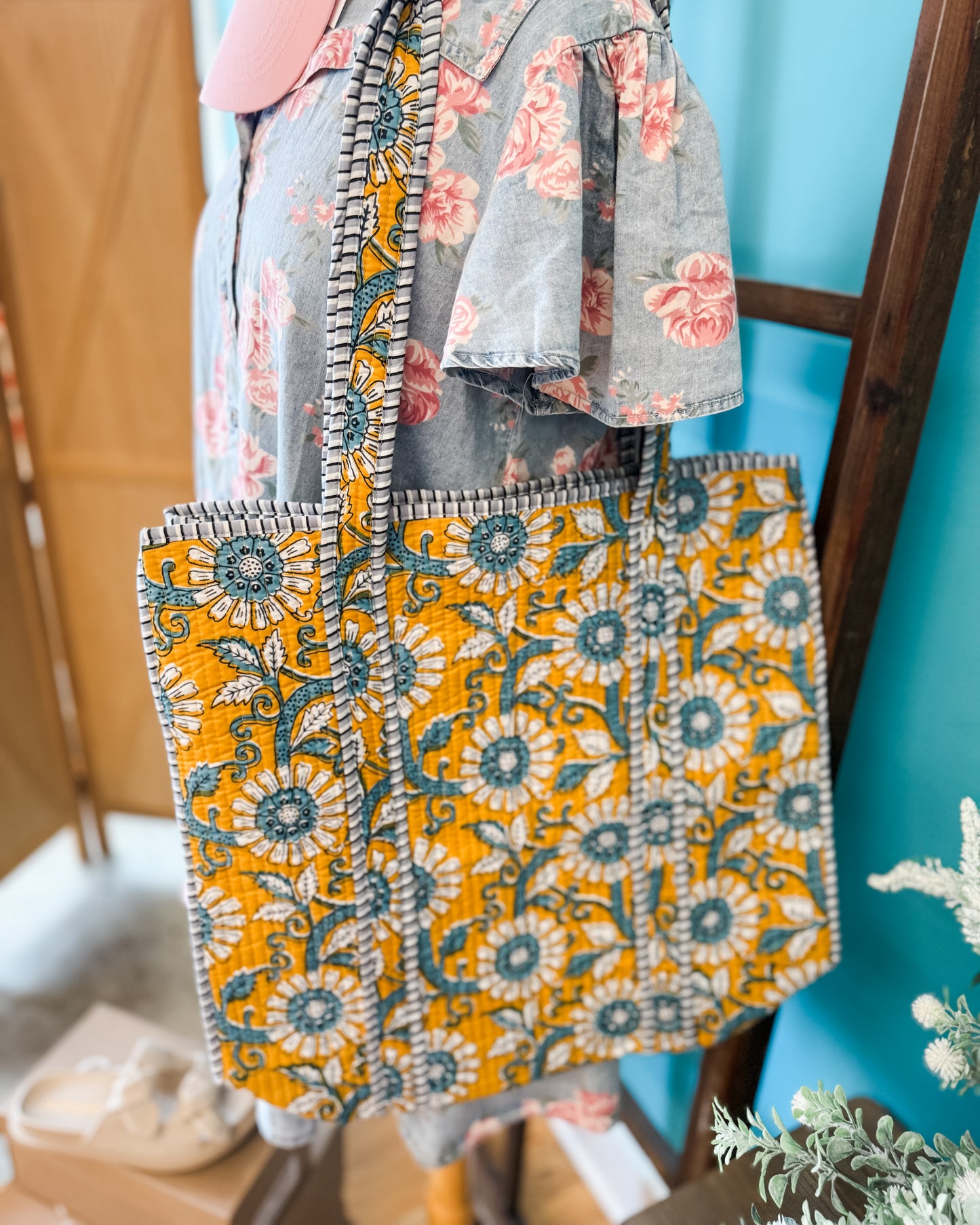 Patterned bag with a floral design held by a person against a blue wall.
