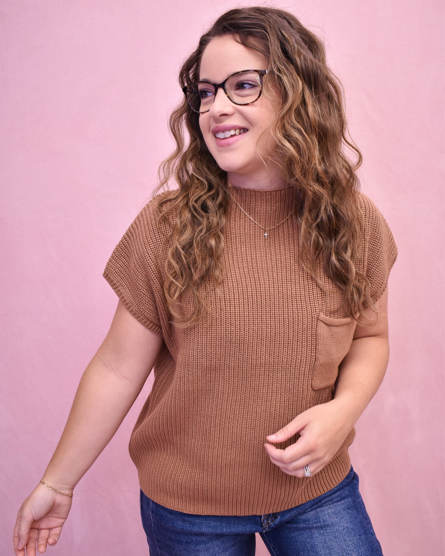 Woman wearing a brown short-sleeve knit top against a pink background