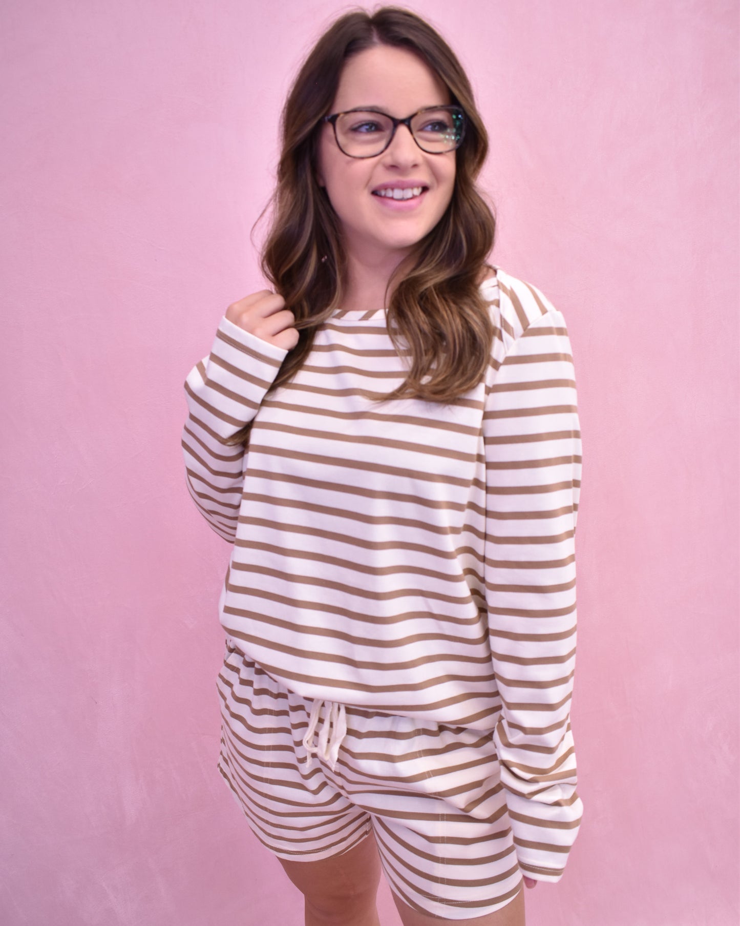 Woman wearing a striped pajama set against a pink background