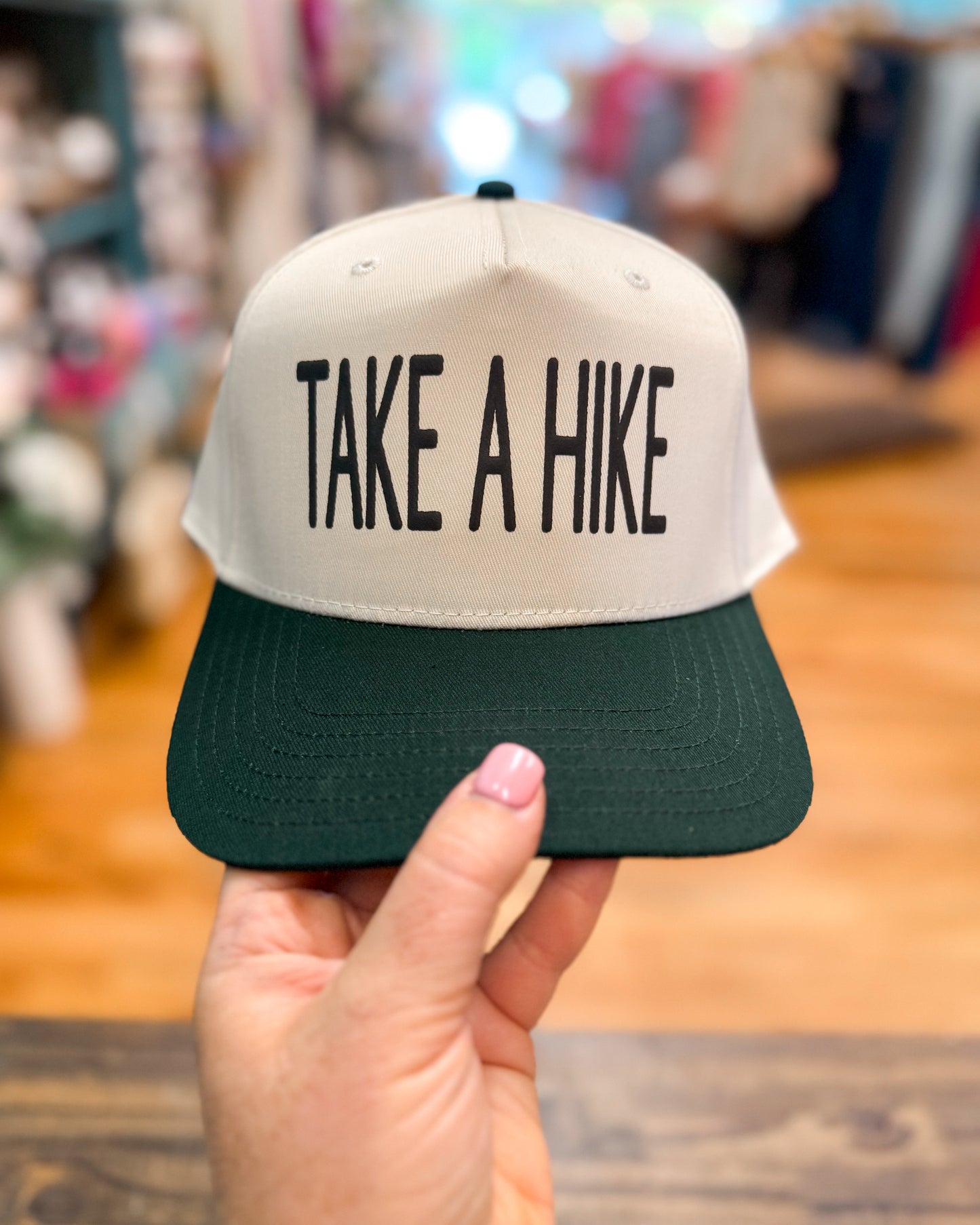 Cap with 'Take a Hike' text held by a hand in an indoor setting