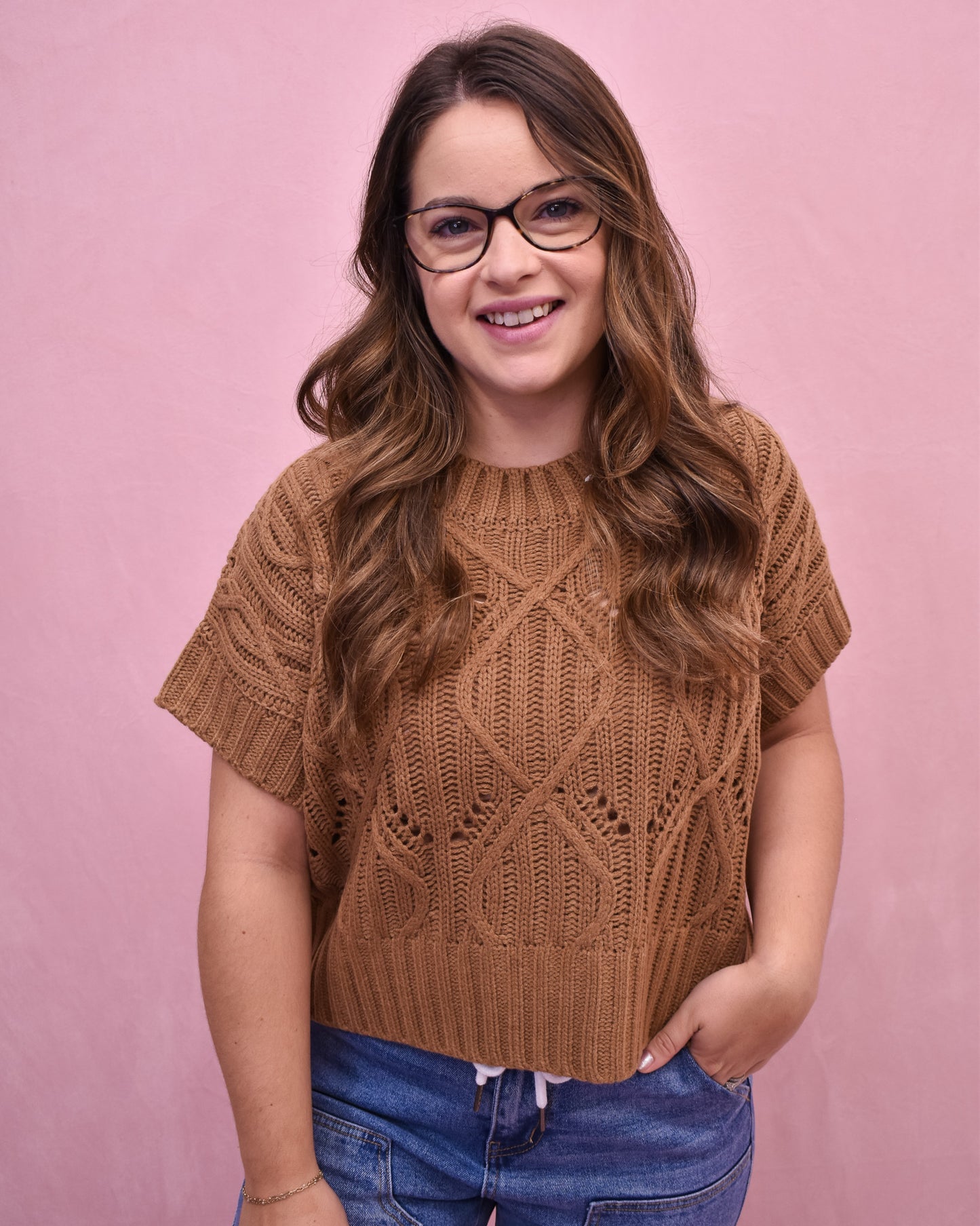Woman wearing a brown knitted top against a pink background
