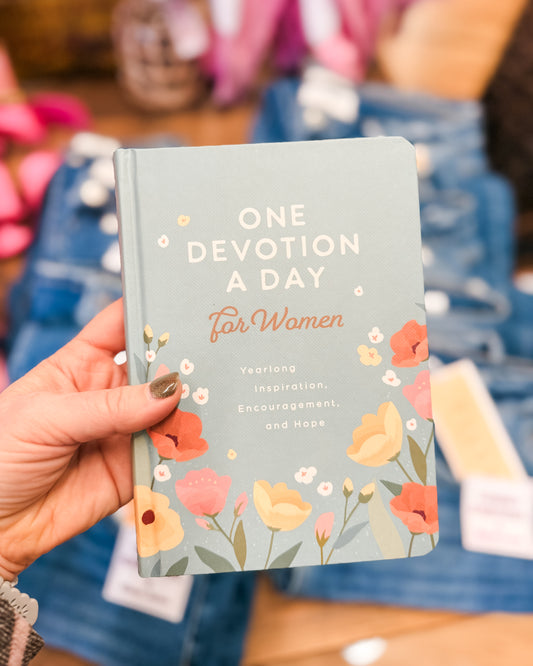 Book titled 'One Devotion a Day for Women' held by a person with floral design on cover