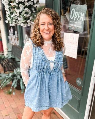 a sleeveless denim romper with pleated vneck, tie front, and pearls all over. paired with a lace layering top.