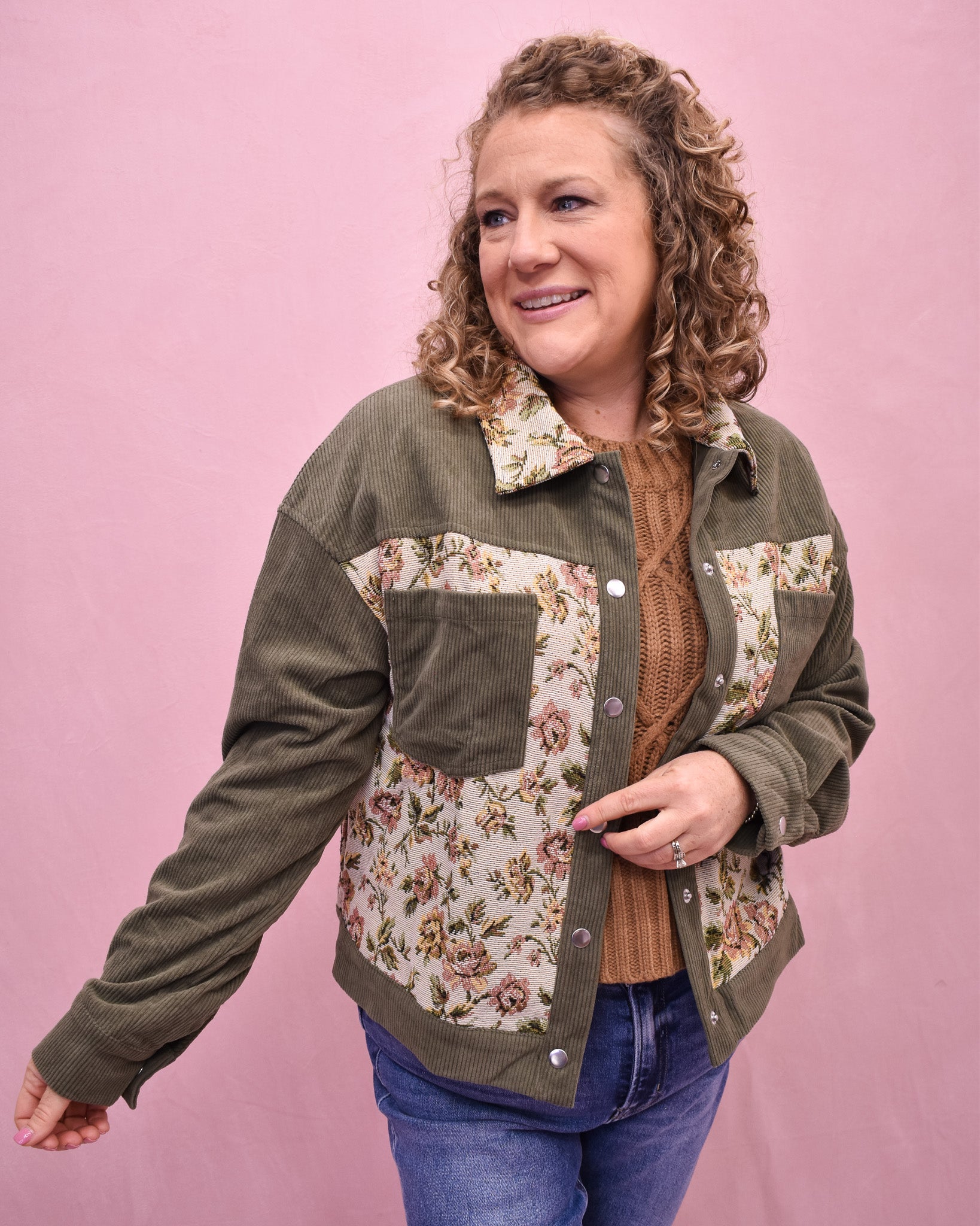 Woman wearing a green jacket with floral patterns on a pink background
