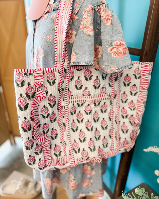 Floral-patterned tote bag with a matching apron against a blue wall.