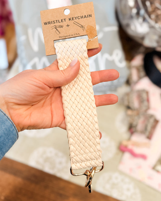 Hand holding a beige woven wristlet keychain 