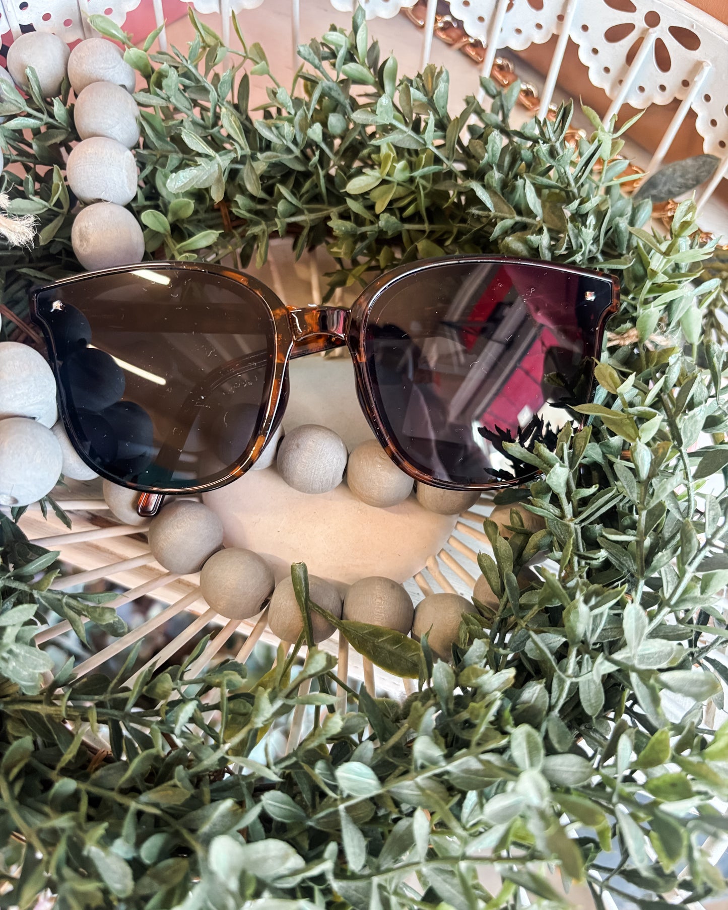 Sunglasses on a decorative wreath with greenery and white berries