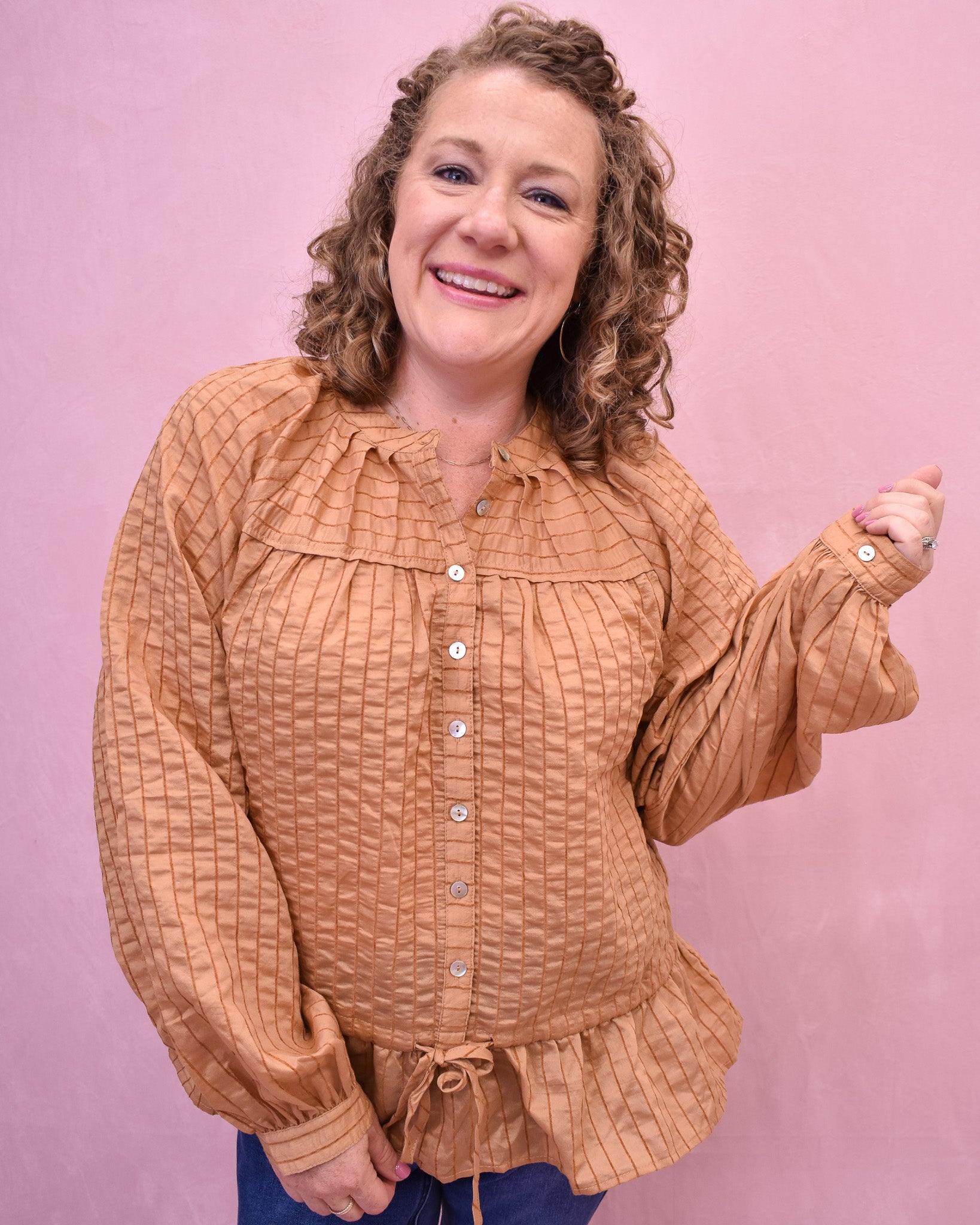 Woman wearing a brown textured blouse against a pink background