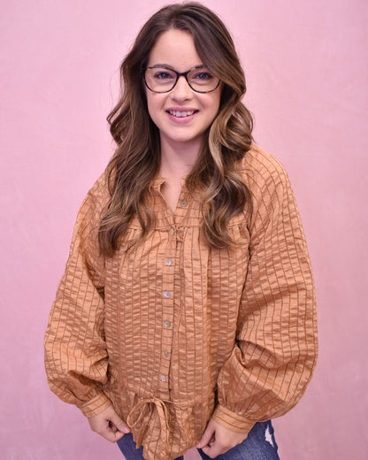 Woman wearing a patterned brown shirt against a pink background