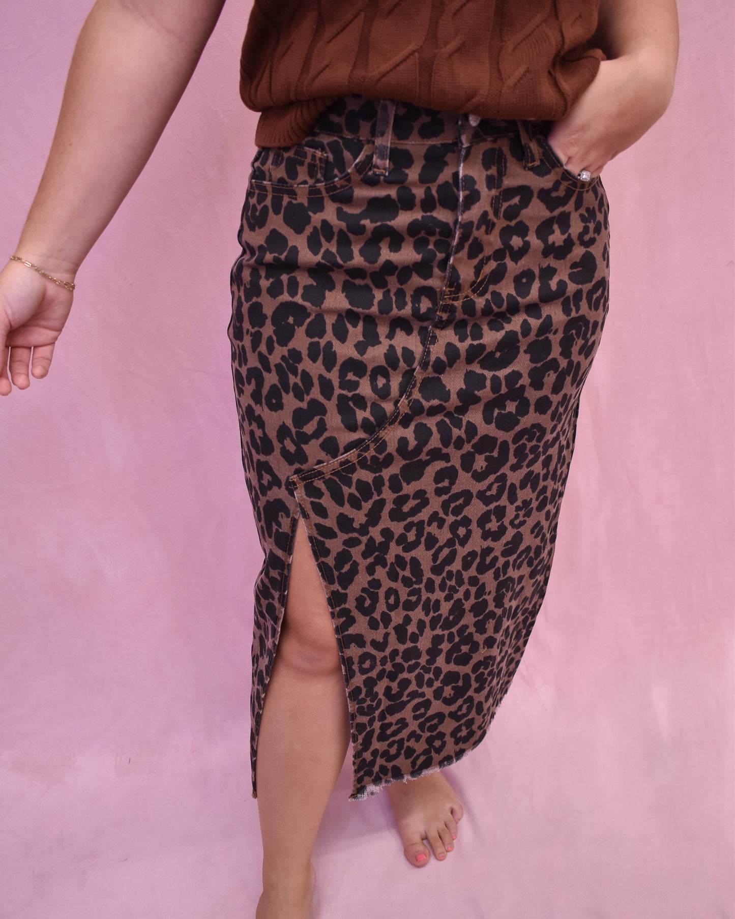 Person wearing a leopard print skirt on a pink background