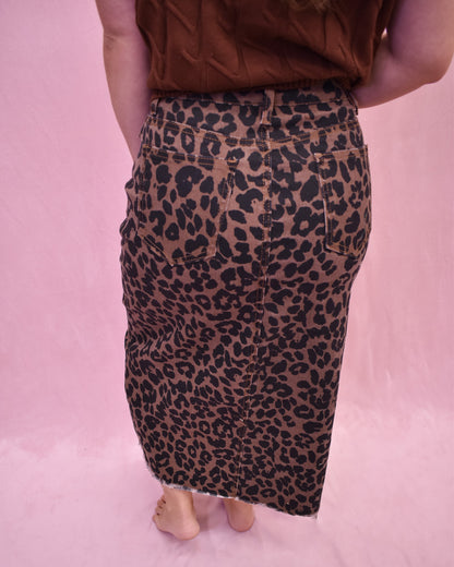 Person wearing a leopard print skirt on a pink background