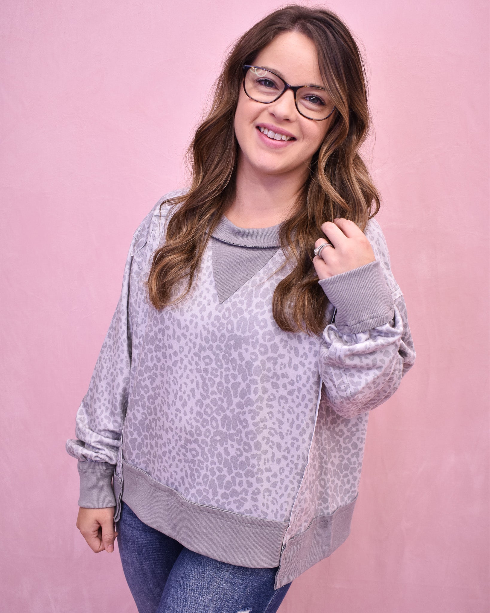 Woman wearing a patterned sweater over a gray shirt on a pink background