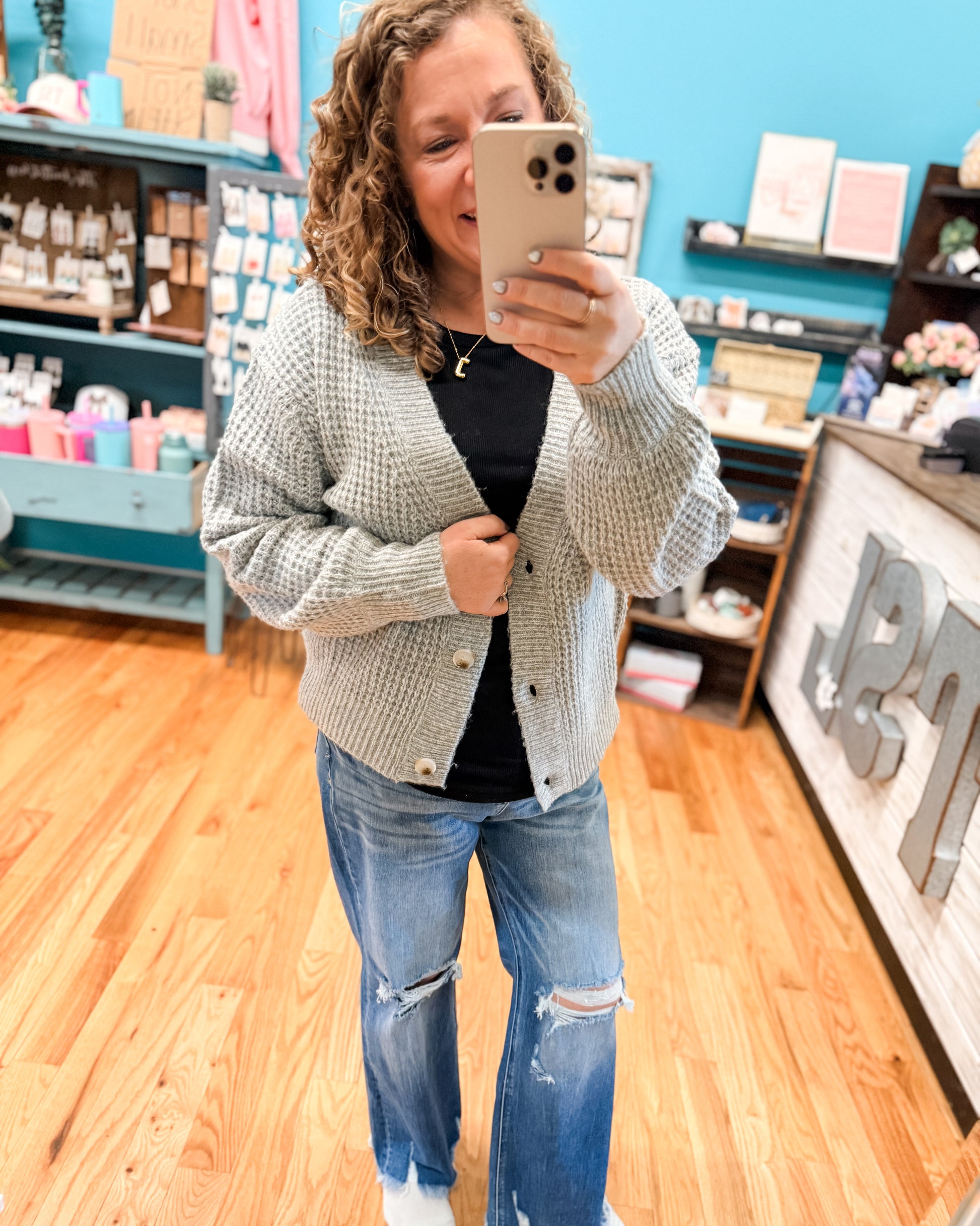Person taking a mirror selfie in a store with shelves and products in the background