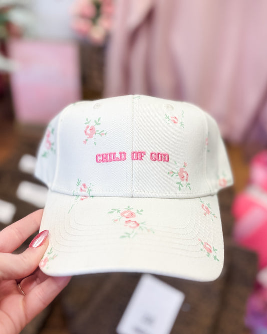Cap with floral patterns and 'CHILD OF GOD' text held by a hand.