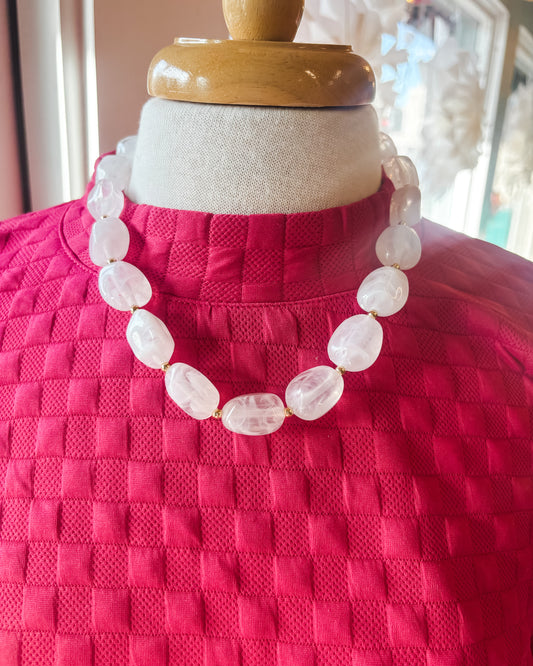 Necklace on a mannequin wearing a pink textured garment