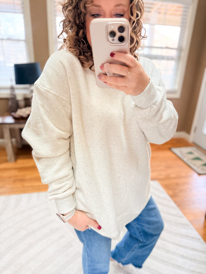 Person wearing a white sweatshirt and blue jeans taking a mirror selfie.