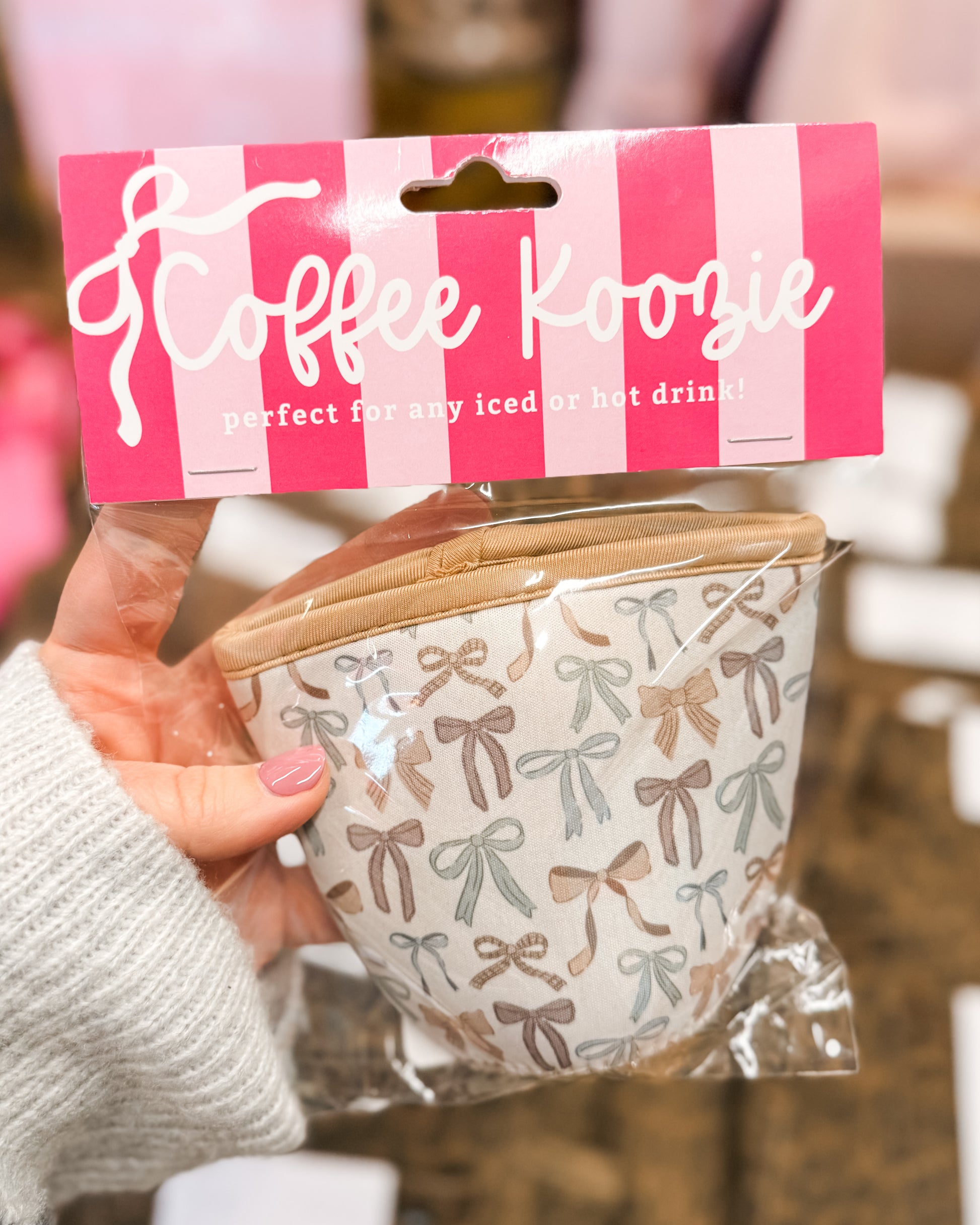 Coffee cozy with bow pattern in packaging held by a hand