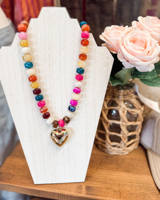 a chunky multi colored beaded necklace with chunky heart charm
