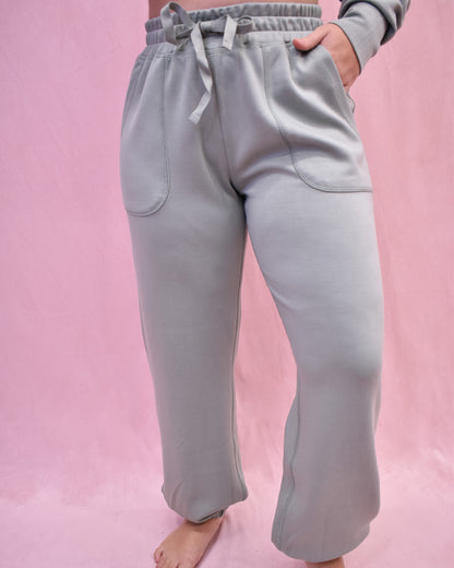 Light gray sweatpants worn by a person on a pink background