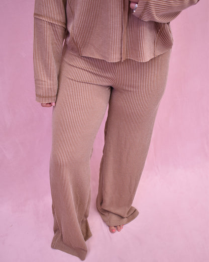 Person wearing a ribbed brown outfit on a pink background
