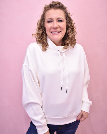 Woman wearing a white hoodie against a pink background