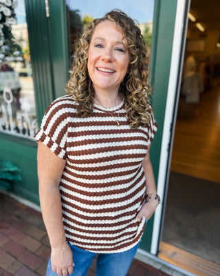 a short sleeve textured round neck and round hem top with cuffed sleeves and brown and cream stripes.