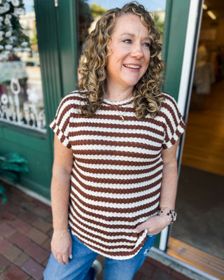 a short sleeve textured round neck and round hem top with cuffed sleeves and brown and cream stripes.