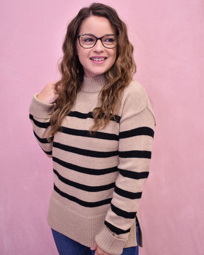 Woman wearing a striped sweater against a pink background