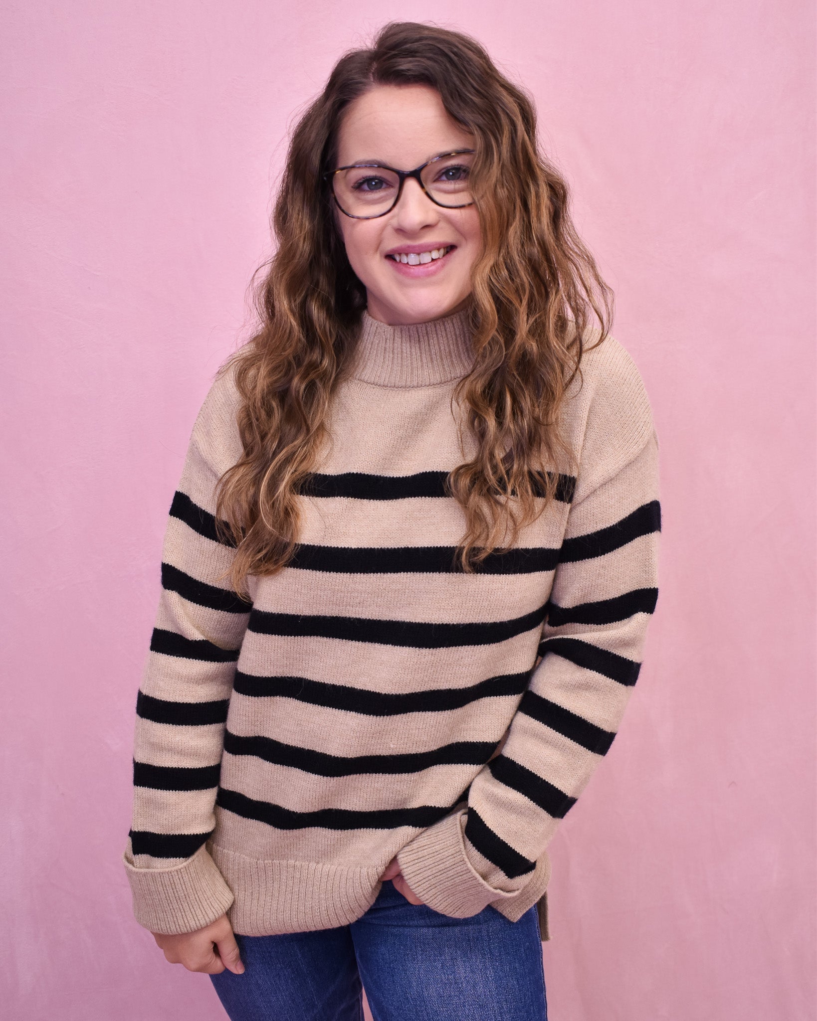 Woman wearing a striped sweater against a pink background