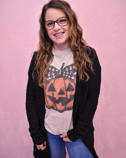 Person wearing a Halloween-themed t-shirt with a pumpkin design on a pink background