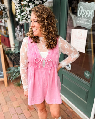 a pink denim shorts romper with pleated vneck and front tie. Paired with a basic lace layering top.