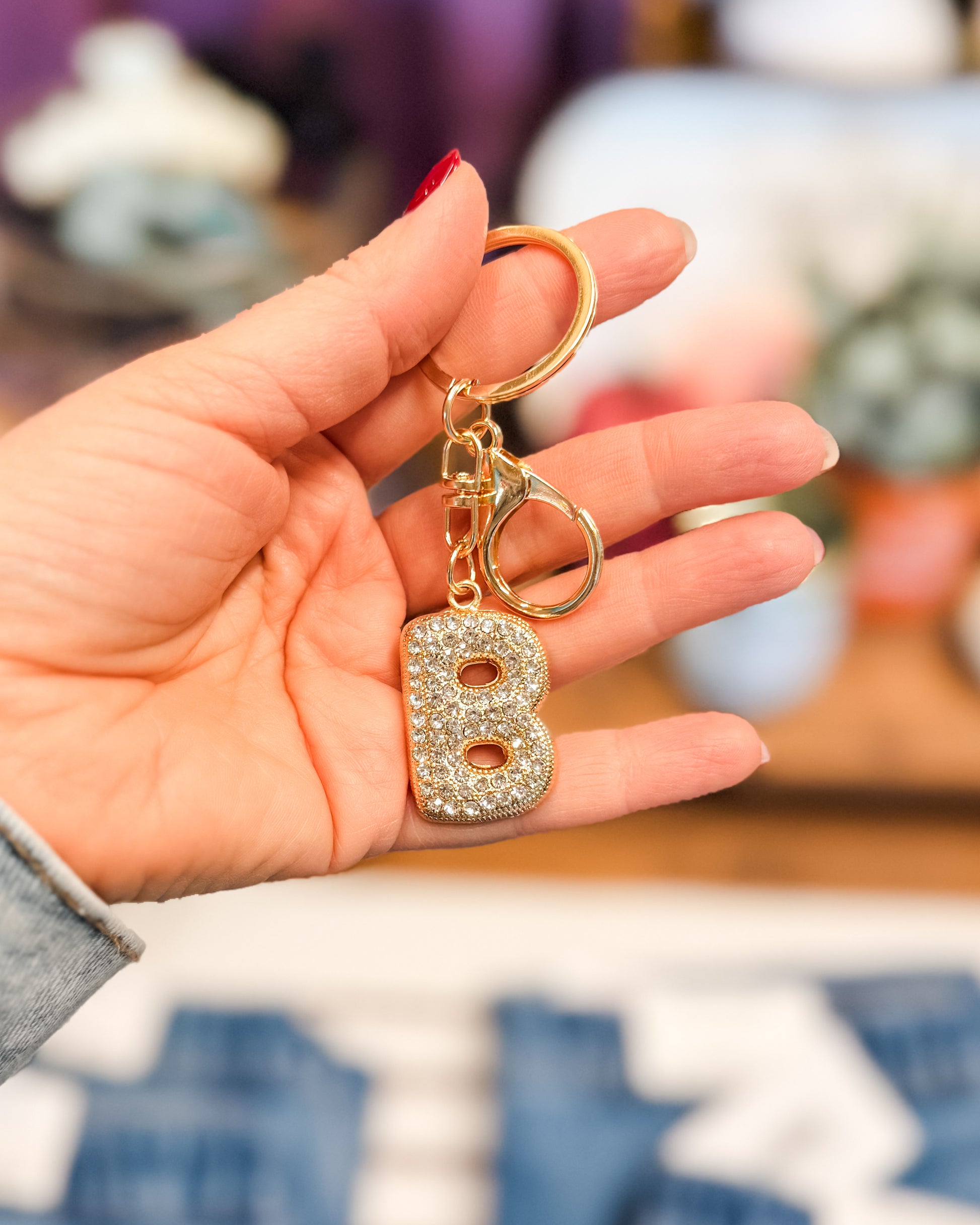 Hand holding a keychain with a letter 'B' charm against a blurred background