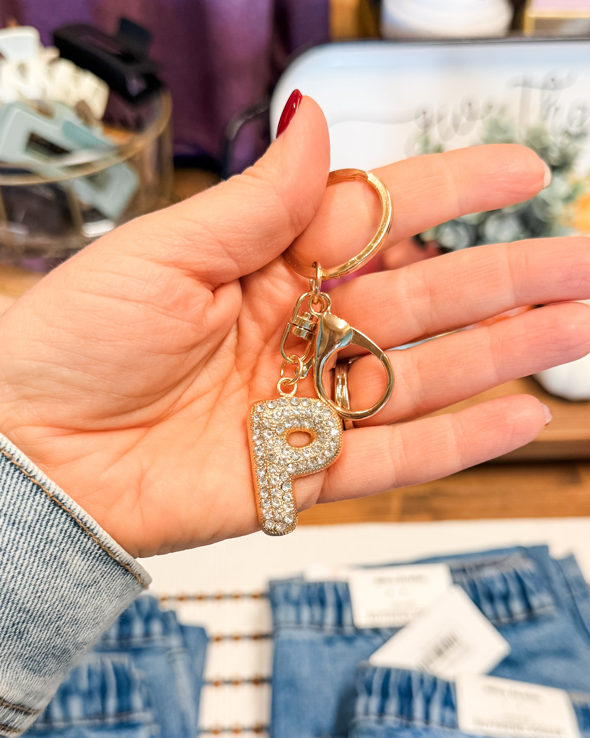 Hand holding a keychain with a letter 'P' charm in a blurred indoor setting
