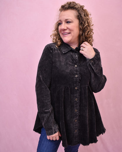 Woman wearing a black button-up shirt against a pink background