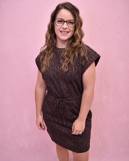 Woman wearing a brown leopard print dress against a pink background