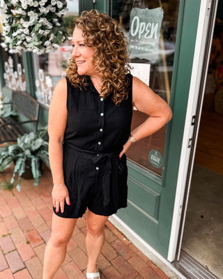 A sleeveless short romper with button down and waist tie