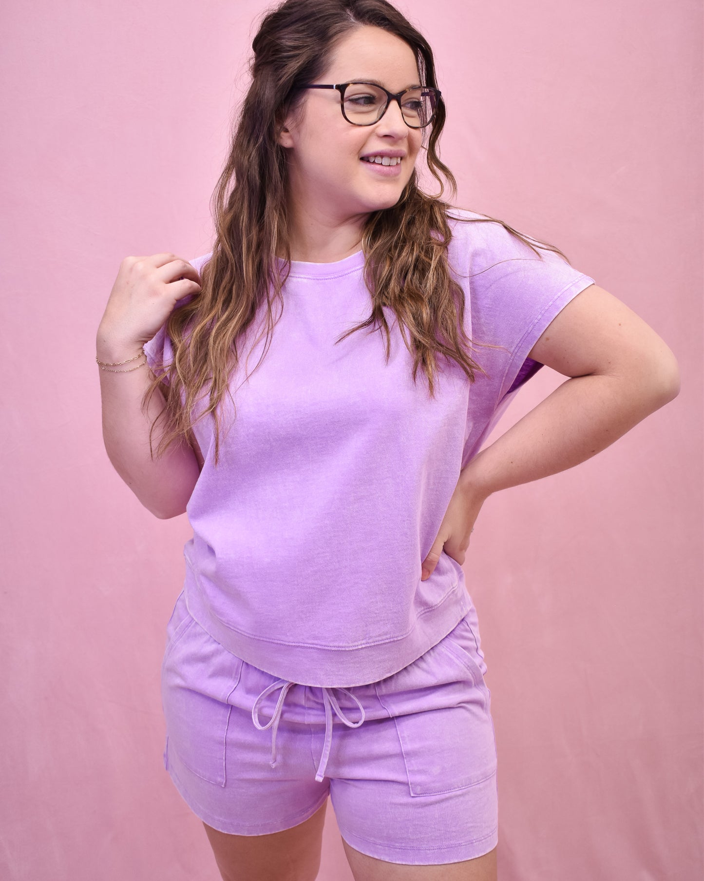 Woman wearing a light purple outfit against a pink background
