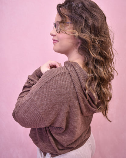 Woman wearing a brown sweater against a pink background