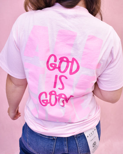 Person wearing a pink tie-dye t-shirt with 'GOD IS GOOD' text on the back against a pink background.