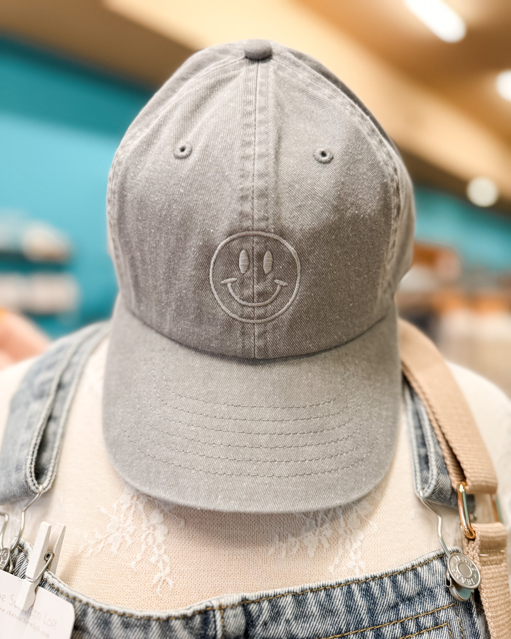 Gray baseball cap with a logo worn by a person in an indoor setting